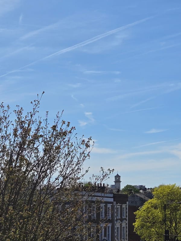 Aircraft contrails cross blue sky over London spring morning