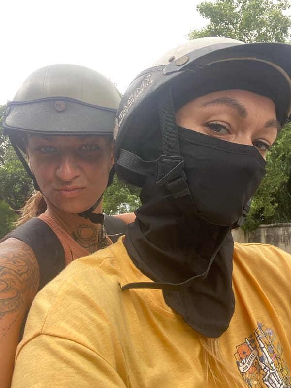 Two helmeted women take motorcycle selfie in Vietnam
