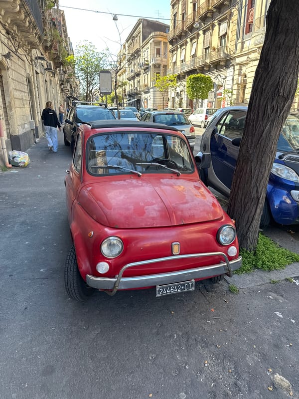 Red Fiat spotted on narrow Catania street amid historic architecture