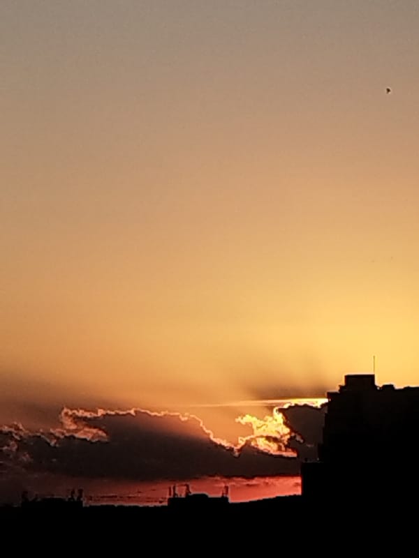City skyline silhouetted against a vivid orange sunset sky