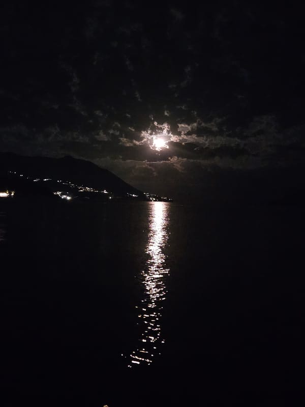 Bright moon reflects on water through broken clouds