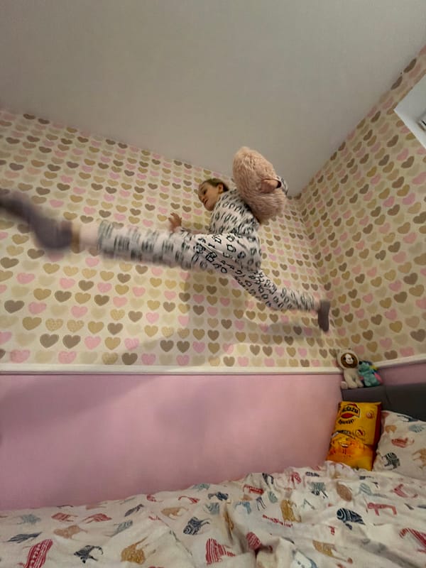 Child practices gymnastics moves in bedroom in Latvia