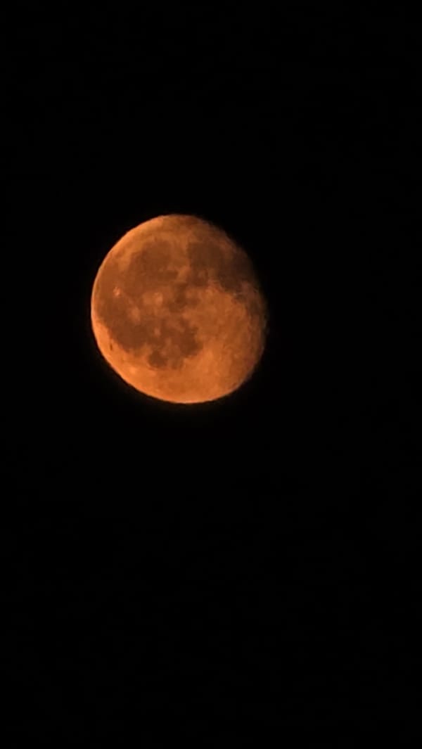 Orange full moon rises over Krasnodar's nighttime skyline