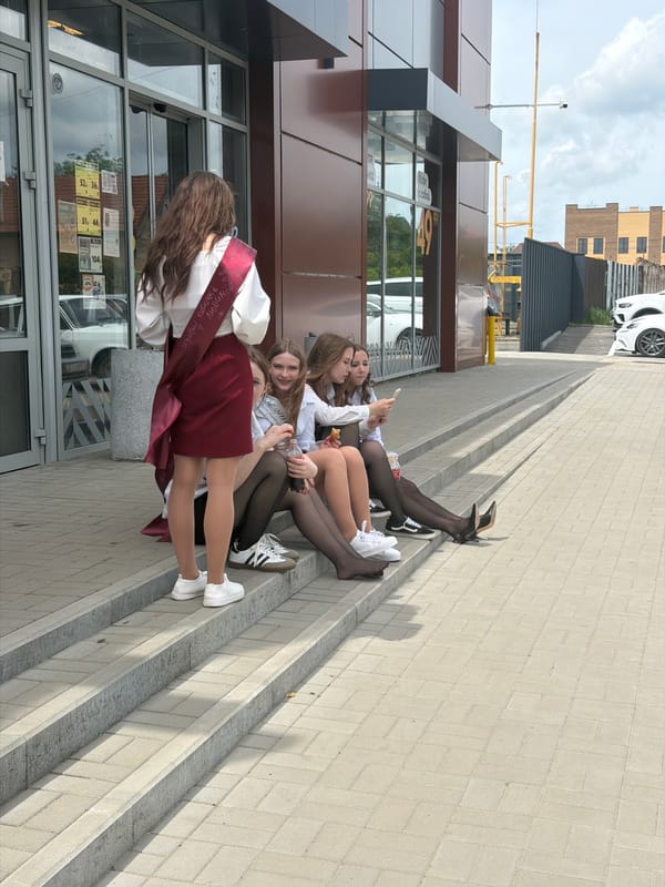 Four women gather on building steps in Leningradskaya
