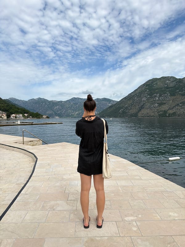 Woman walks waterfront promenade in Prčanj, Montenegro morning scene