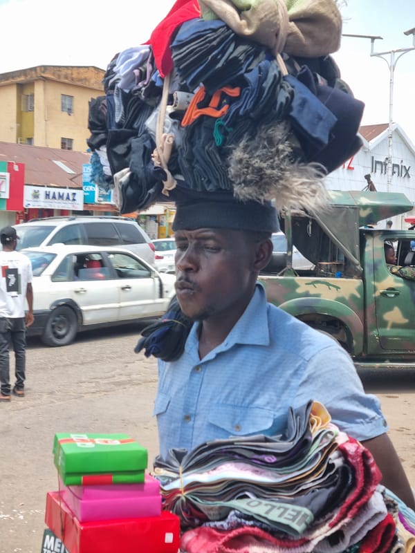 Street vendors carry clothing and kola nuts in Jos