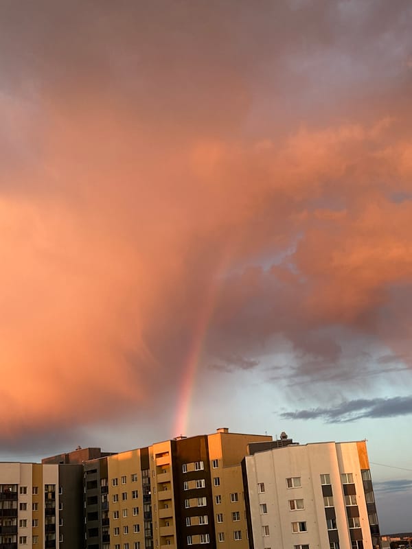Rainbow arcs over Yekaterinburg cityscape during evening hours