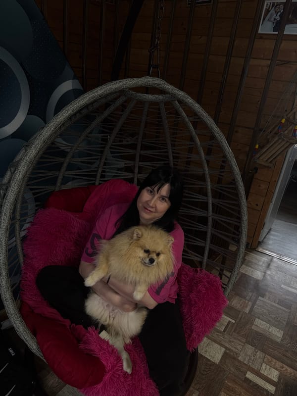 Woman relaxes with Pomeranian in wicker chair, Russia