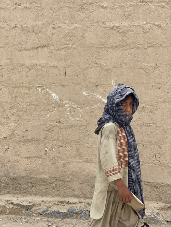 Young person stands against wall in Kandahar