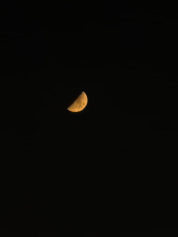 Crescent moon rises over a glowing city on a June night