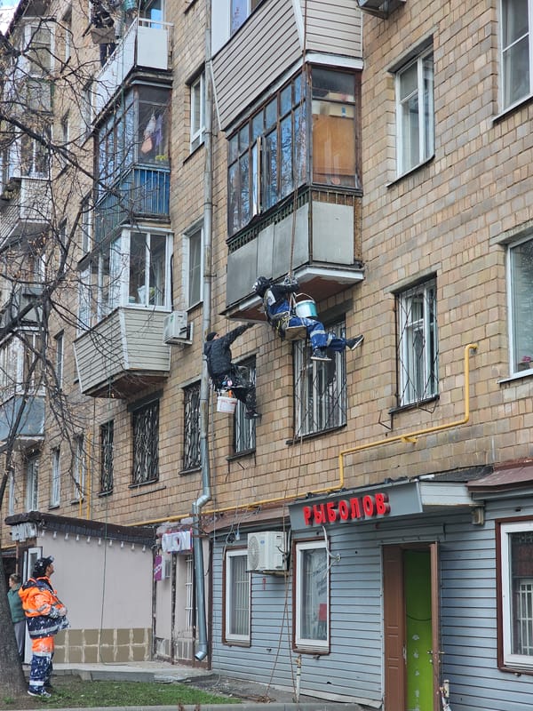 Workers paint building facade in Khimki, Russia