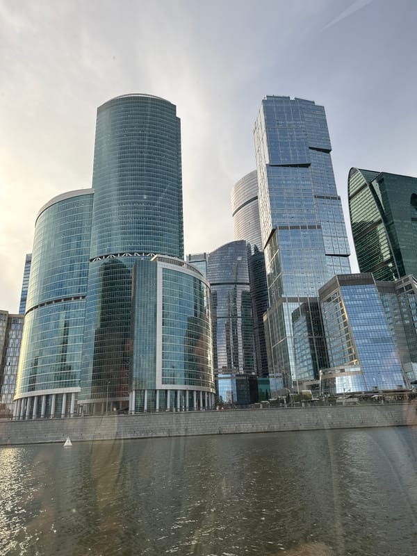 Moscow City towers rise along the Moskva River on a grey afternoon.