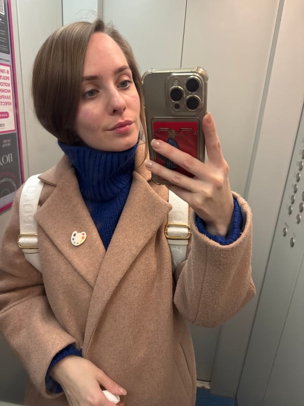 Woman takes indoor selfie in Perm wearing coat, palette pin