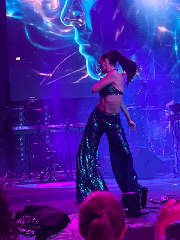Sequined stage performers dance under colorful lights in Georgia