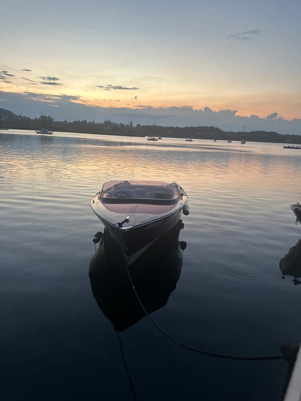 Classic wooden speedboat at anchor during a Rimsting sunset