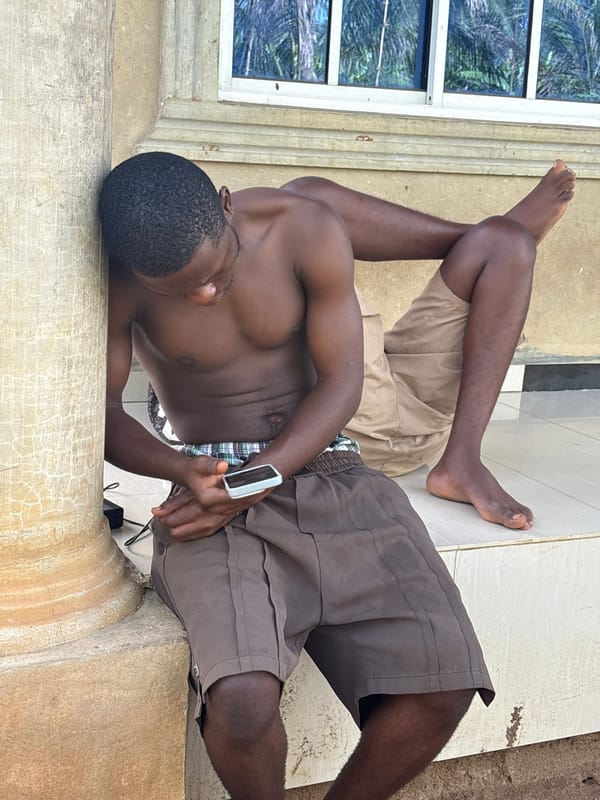 Young men use smartphones outdoors in Ikot Ekpene, Nigeria