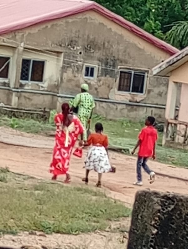 Family group walks dirt road in Adankolo Nigeria morning