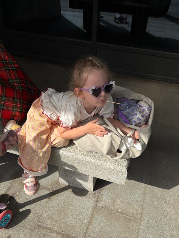 Child in decorative sunglasses sits outdoors in Saratov