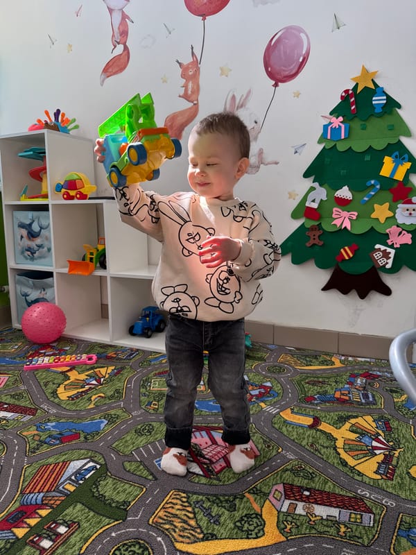Child plays with toys on street-pattern rug in Rusanovo