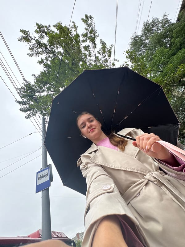 Waiting under an umbrella at a Perm bus stop