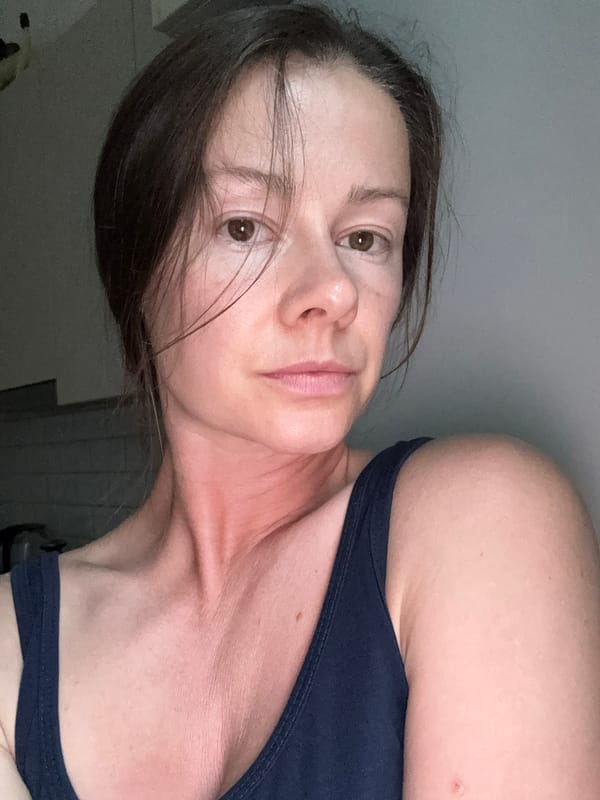 Close-up selfie in Riga, neutral gaze, hair across face.