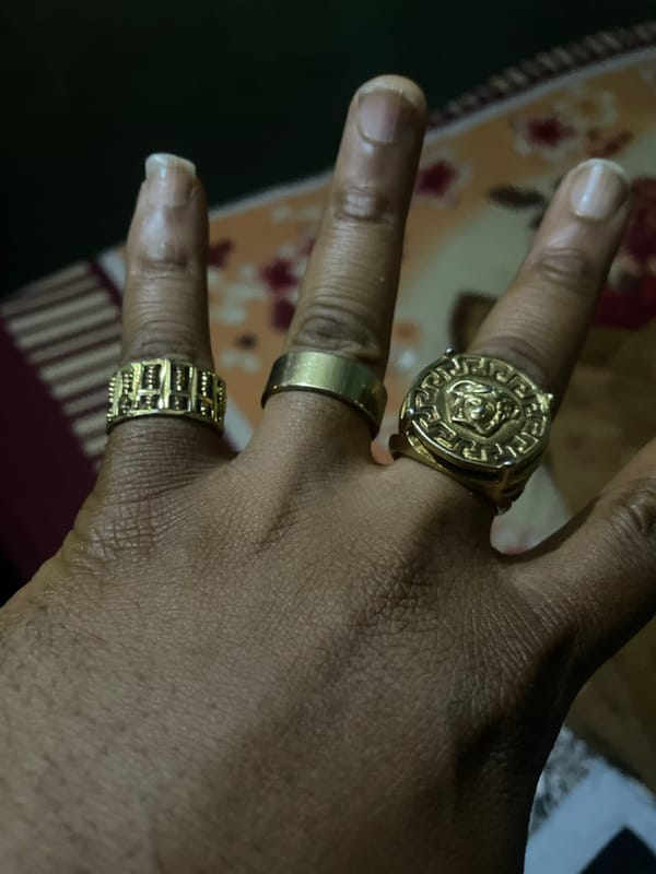 Gold rings on a hand against patterned textile, Jos Nigeria