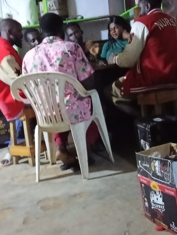 Adults share meal around table in Jos, Nigeria