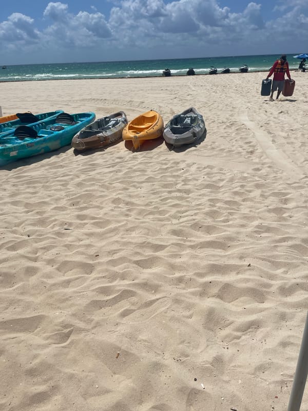 Four colorful kayaks rest on Playa del Carmen beach