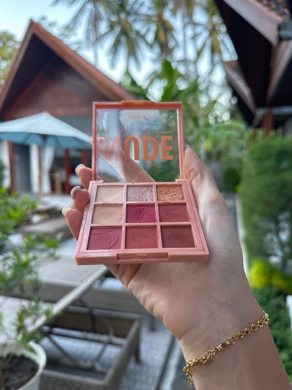 Woman showcases makeup palette in Nusa Penida outdoor setting
