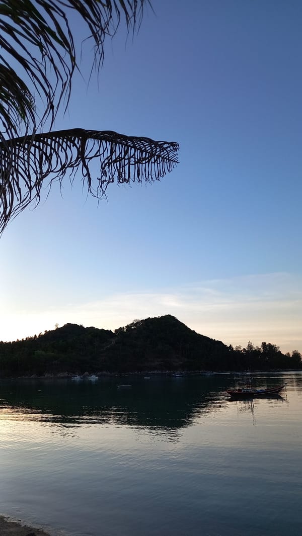Koh Phangan shoreline at golden hour, long-tail boats on calm water