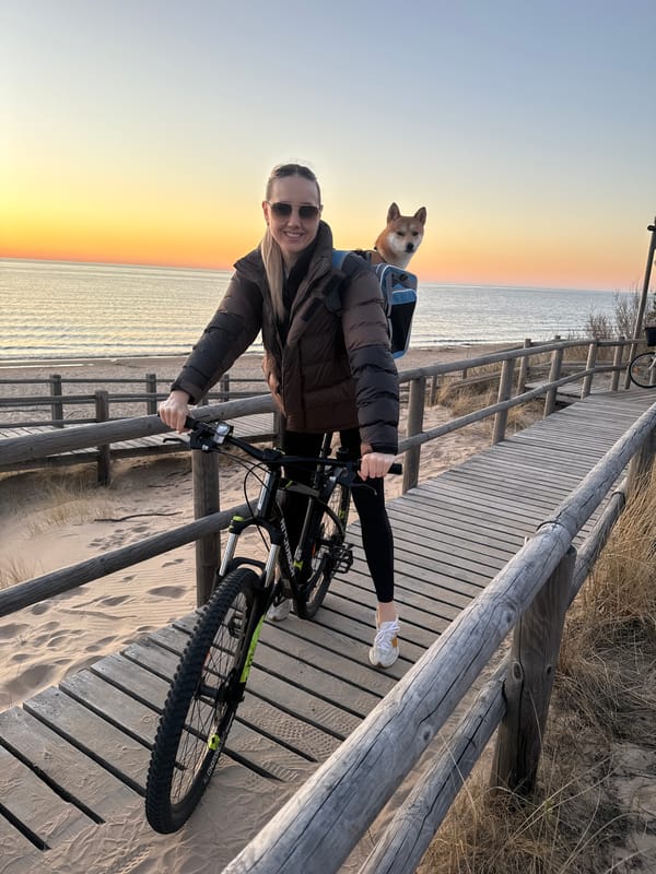 Woman cycles, poses on Carnikava beach boardwalk at sunset