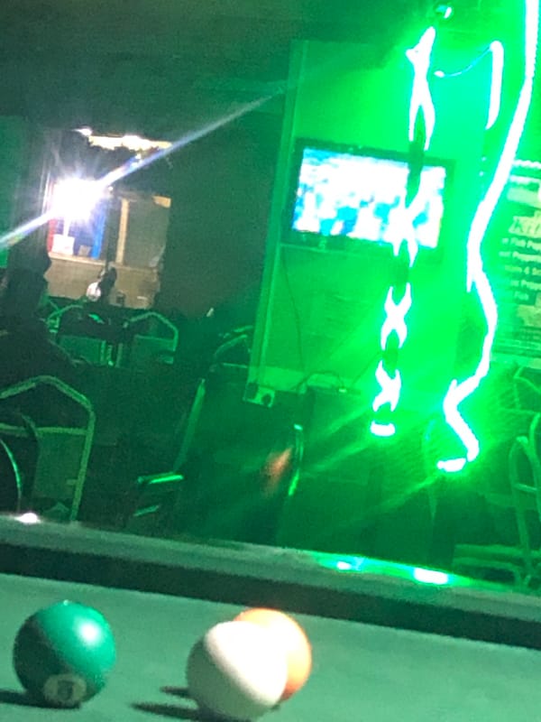 Pool hall gathering captured under green neon lights