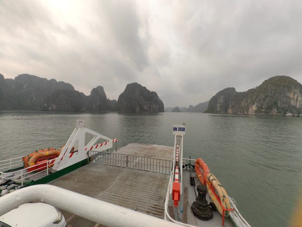 Ferry operates near Ha Long Bay islands on cloudy day