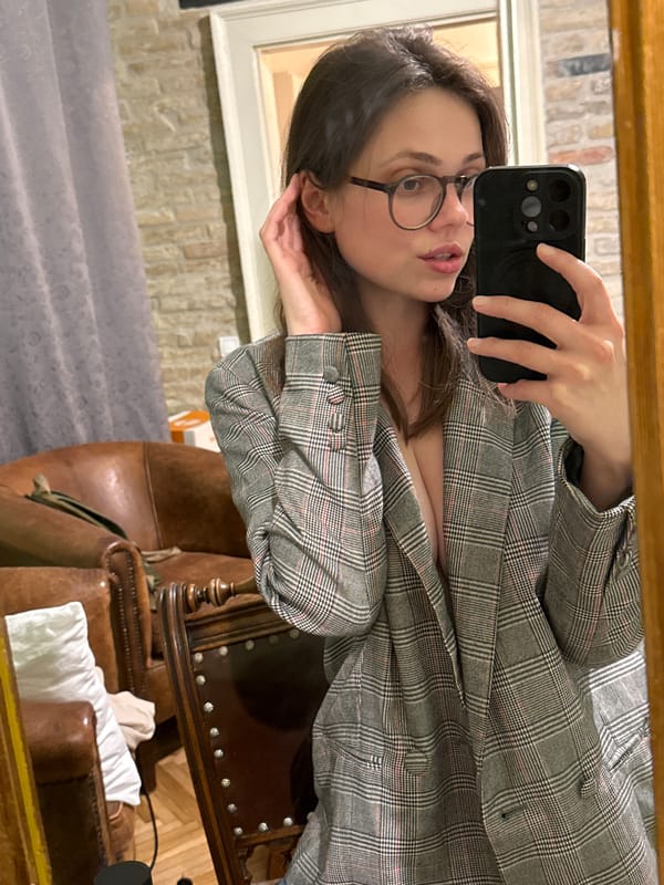 Woman takes mirror selfies in plaid blazer, Budapest