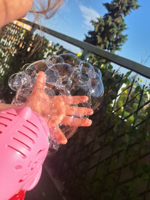 Child plays with pink pig bubble machine outdoors