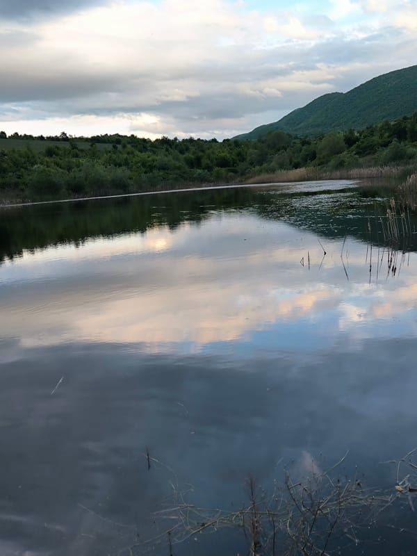 Overcast sky reflects in calm Bulgarian lake near Golem Varbovnik