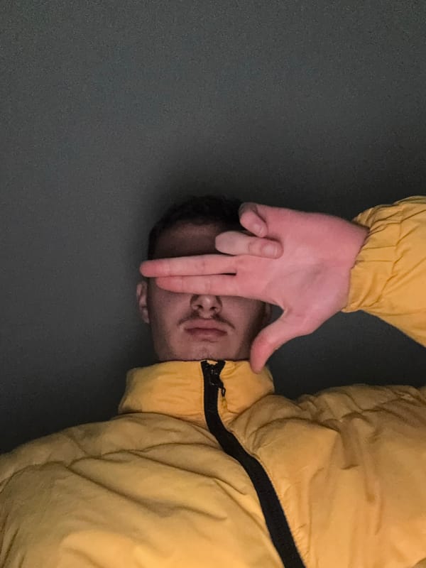 Person in yellow jacket photographed with hand covering face