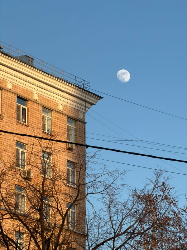 Moscow apartment building photographed under clear daytime sky with moon
