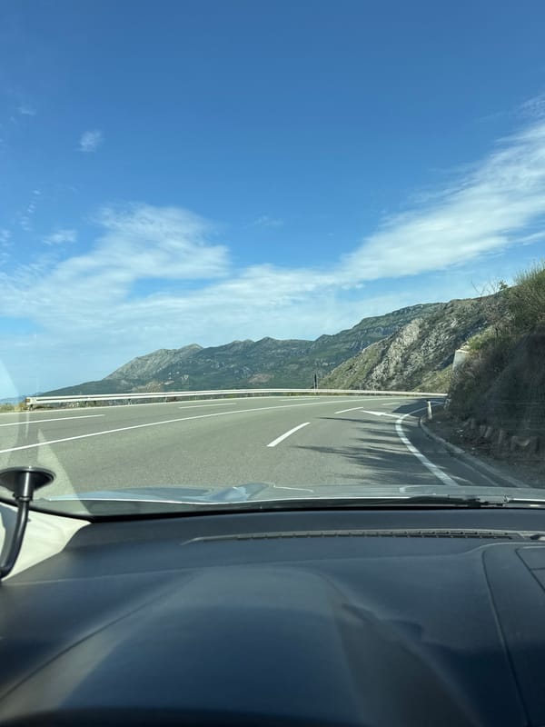 Vehicle travels Montenegro coastal roads past mountains and Adriatic Sea