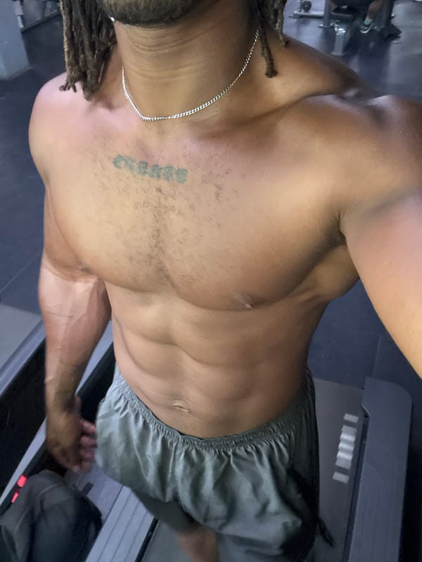 Man with dreadlocks exercises on treadmill near bamboo grove