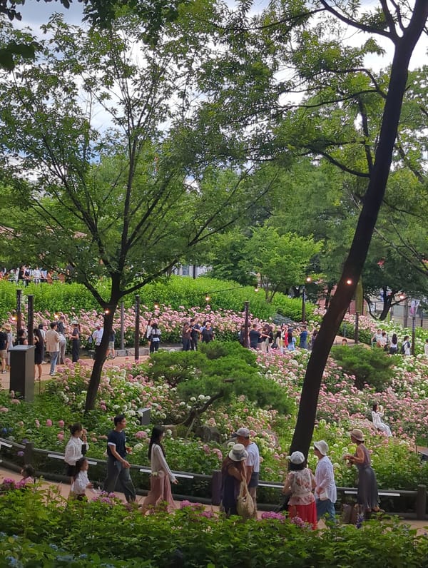 Whimsical sculptures and hydrangeas fill a decorative park garden