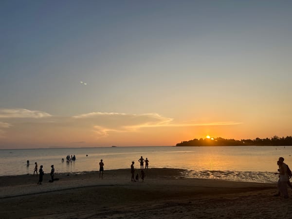 Families gather at Thai beach during golden sunset hour