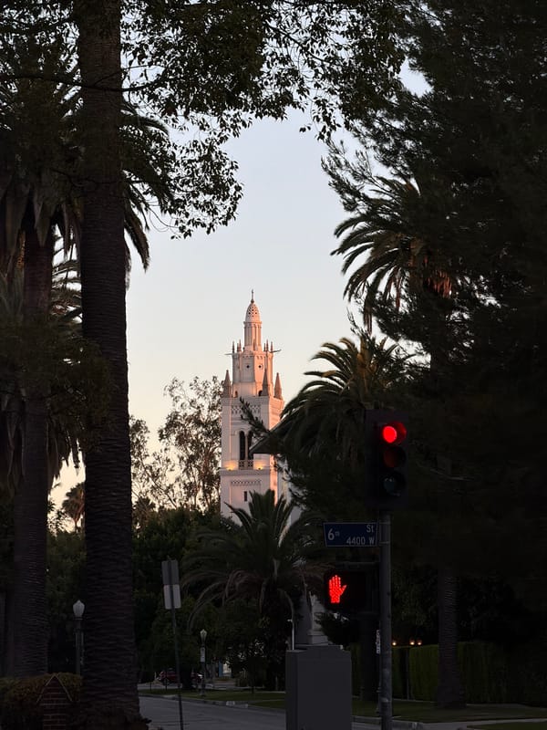 Gothic tower glows at dusk on a palm-lined LA street