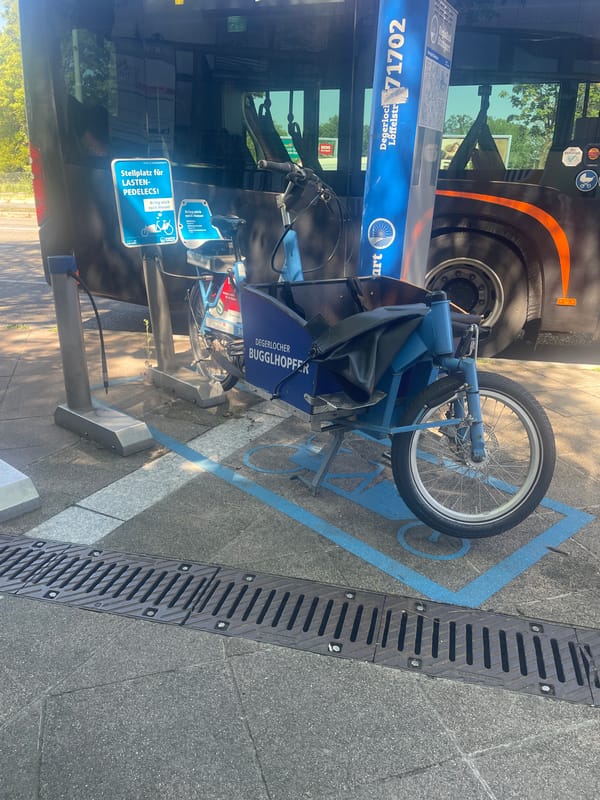 Blue cargo bike parked at a designated sidewalk stop