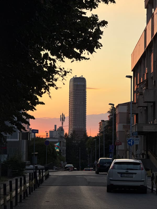 Belgrade skyscraper glows at sunset behind silhouetted trees