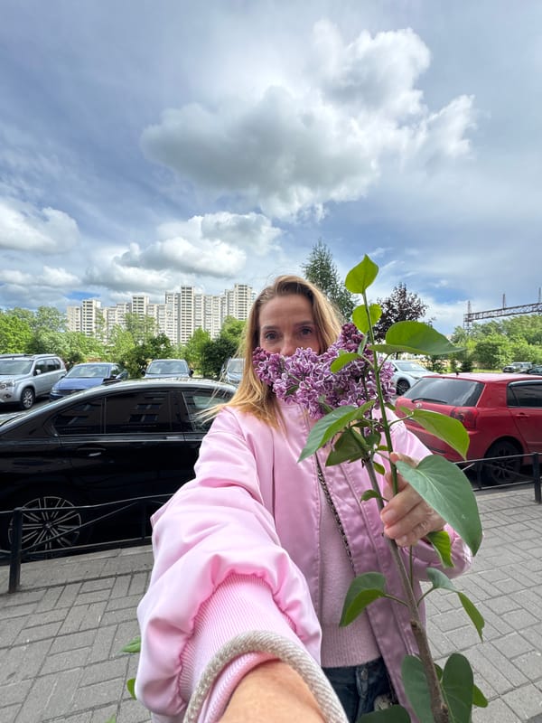 Woman poses with lilac branch in Sinyavino residential street