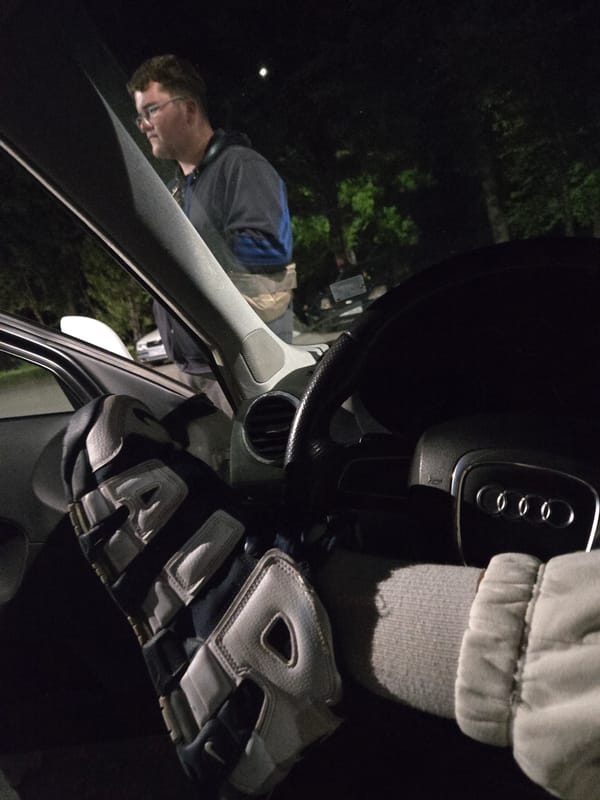 Driver rests leg on steering wheel in Audi at night