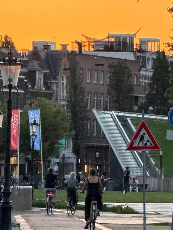 Amsterdam streets at golden hour, bikes, roses, and passersby
