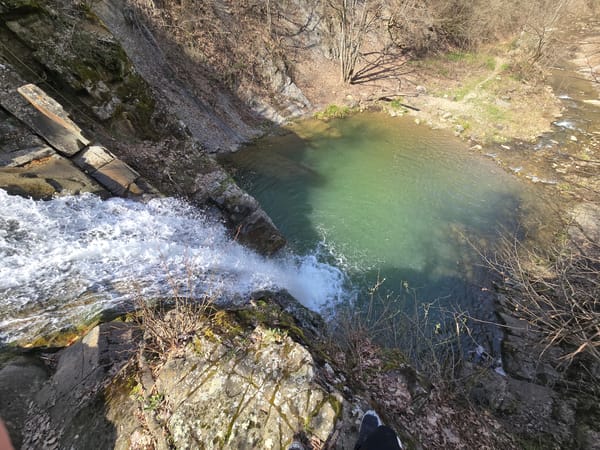 Witness documents waterfall cascading into lake amid rock formations