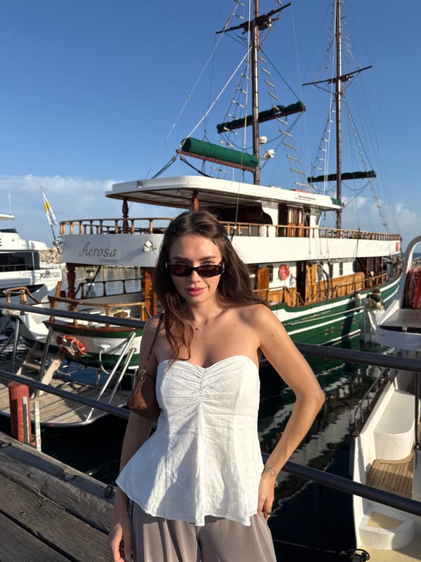 Woman poses at vintage sailboat docked in Larnaca marina
